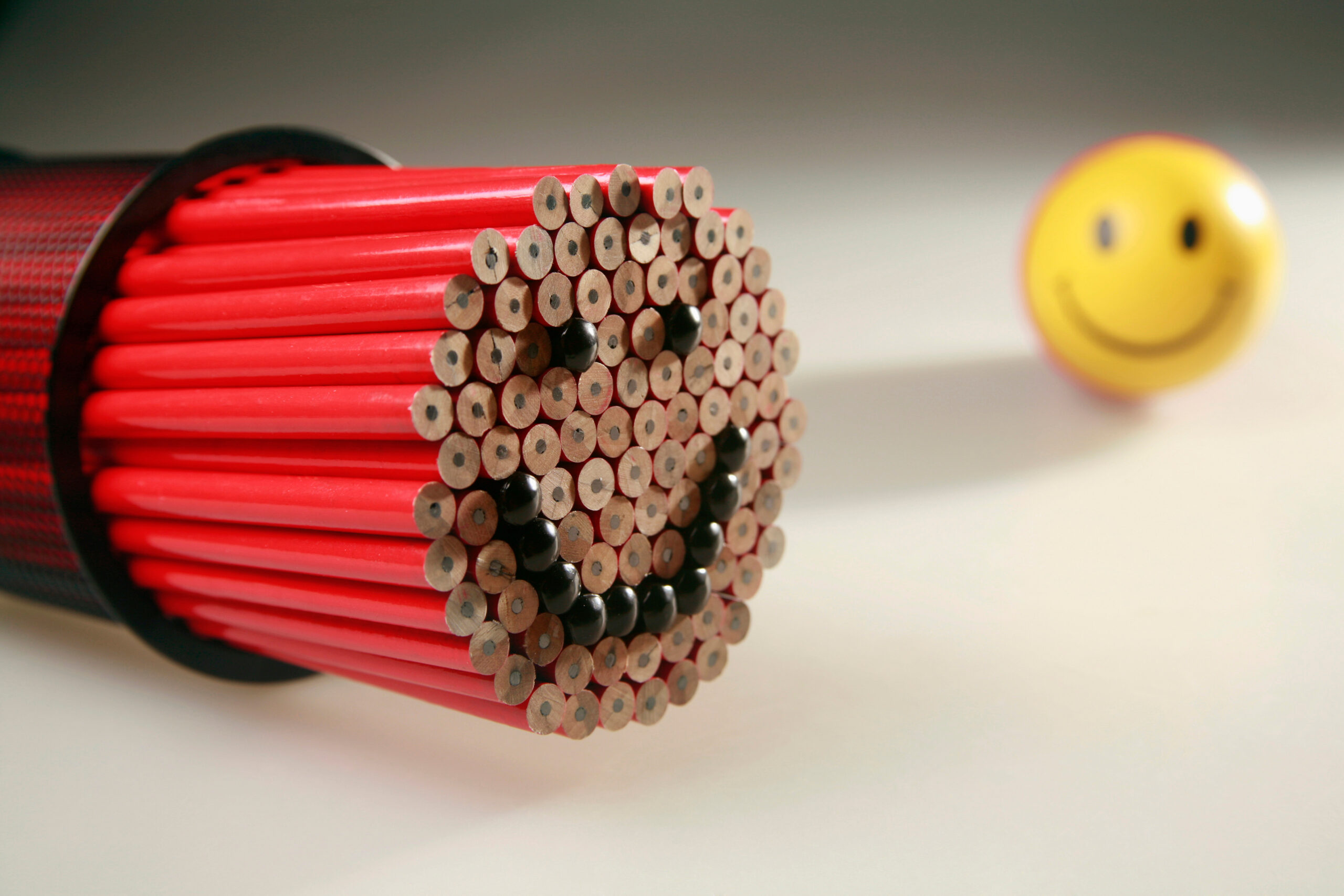 Bundle of pencils with smiley face, stress ball on cup in the background